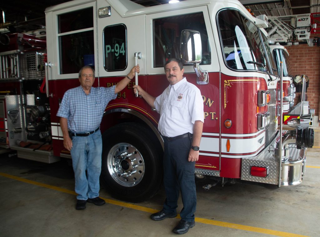 Sidney Perry, left, and his son Chris Perry standing beside a Zebulon fire engine